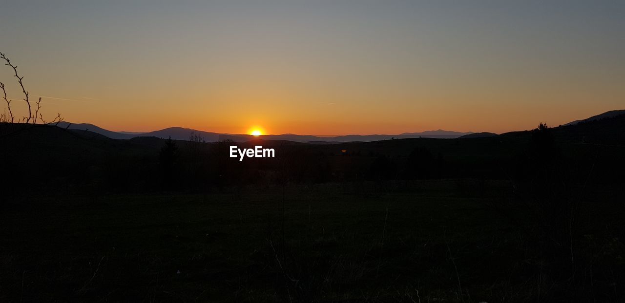 SCENIC VIEW OF SILHOUETTE MOUNTAINS AGAINST CLEAR SKY AT SUNSET