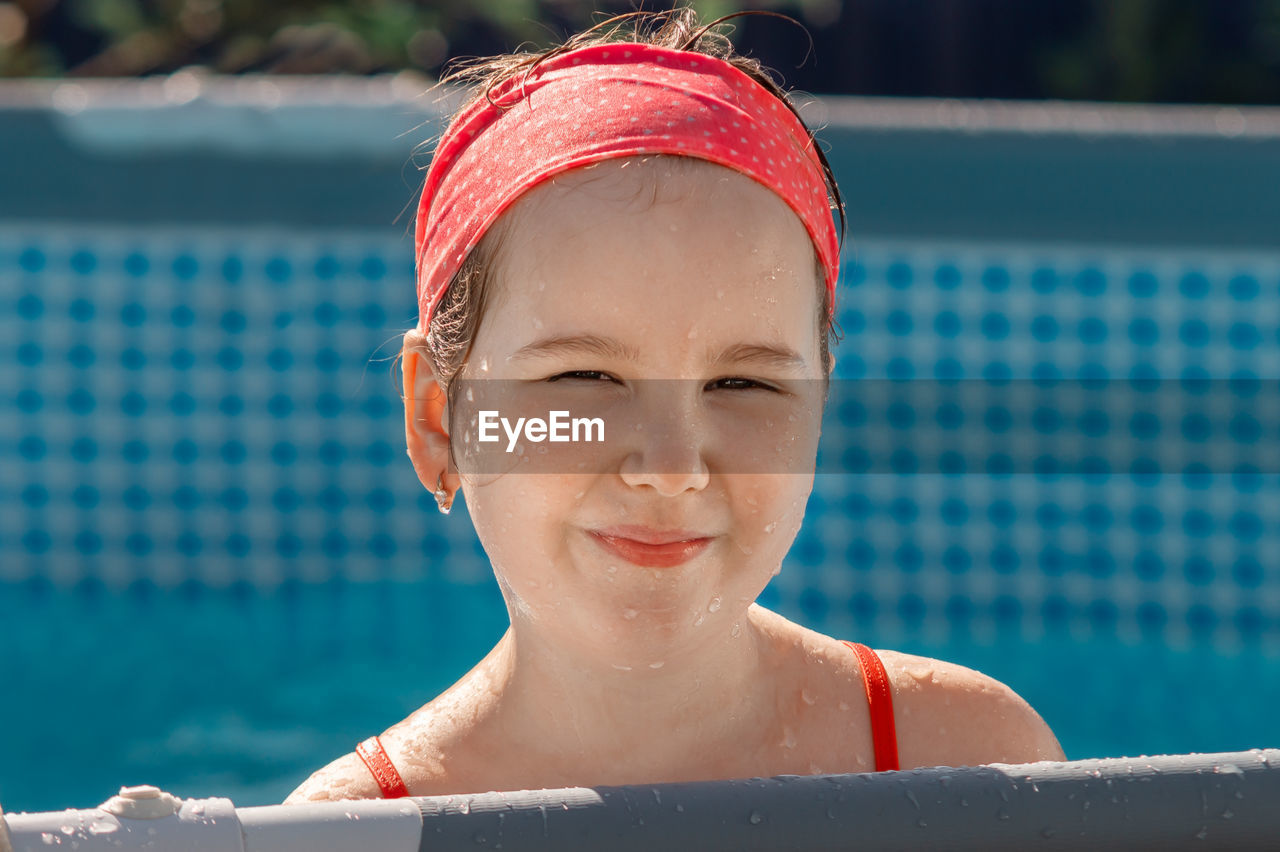 Lovely smiling girl in kiddie pool at summer sunny day. 