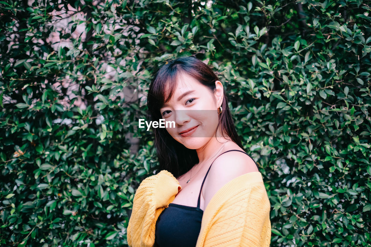 Portrait of smiling woman standing against plants