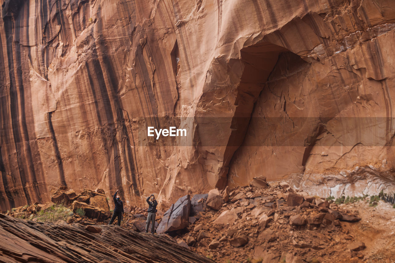 People below high sandstone canyon walls near escalante river, utah