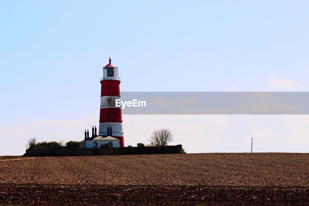 Low angle view of lighthouse by building against sky