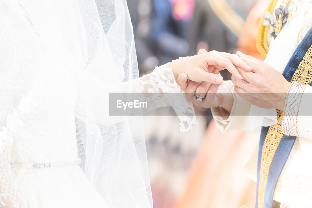 Midsection of bride and groom during wedding ceremony