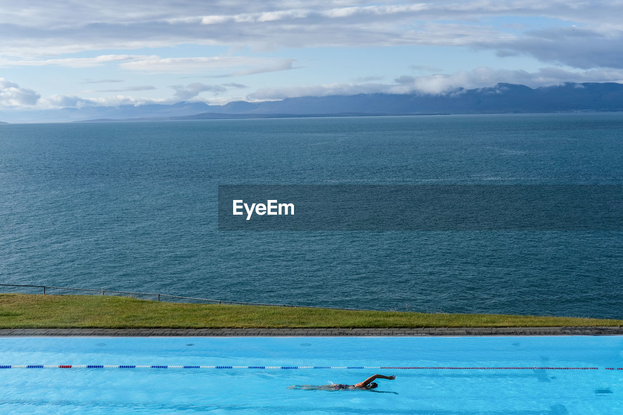 Person swimming in pool against sea