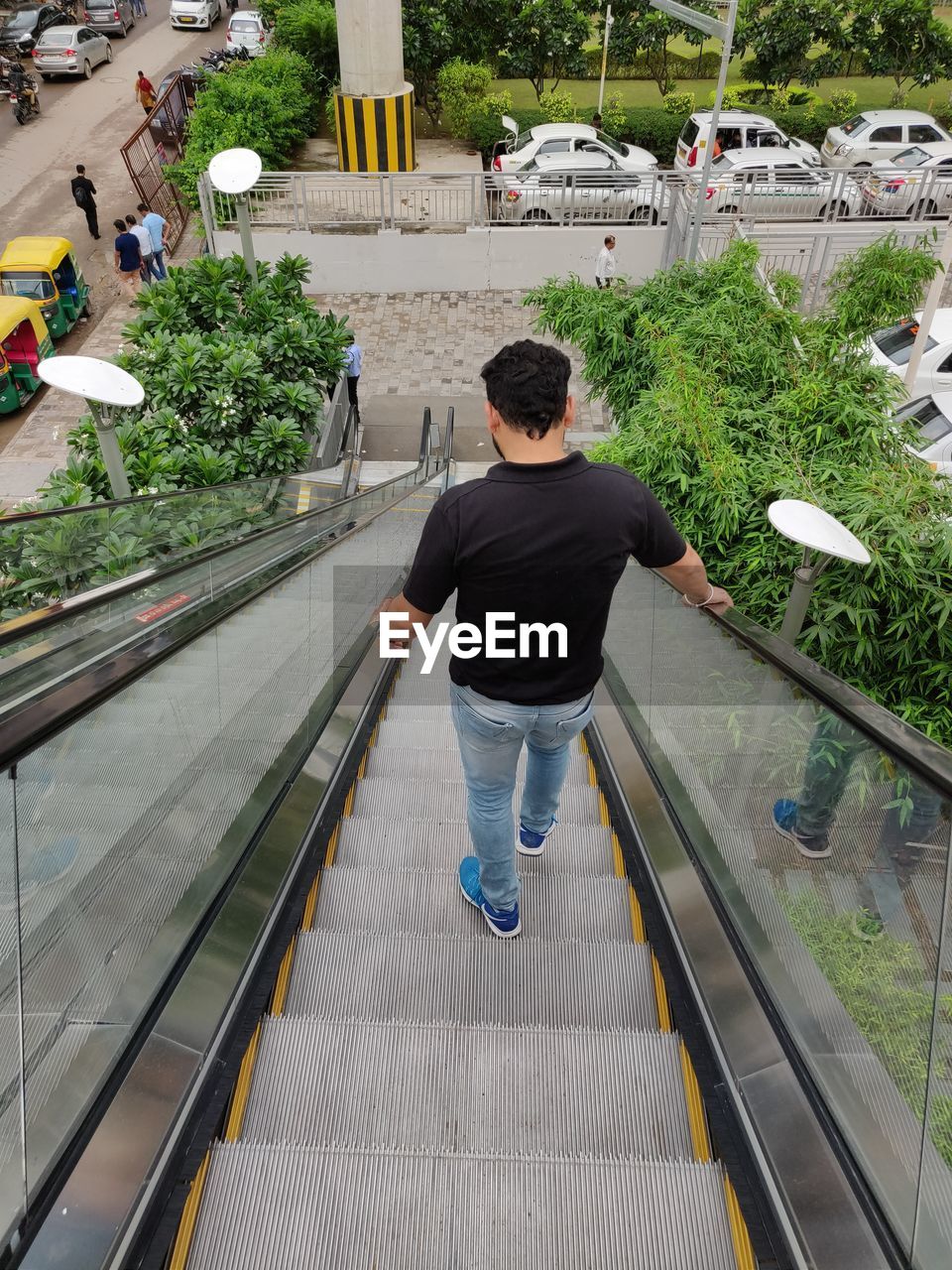 Rear view of mid adult man standing on escalator