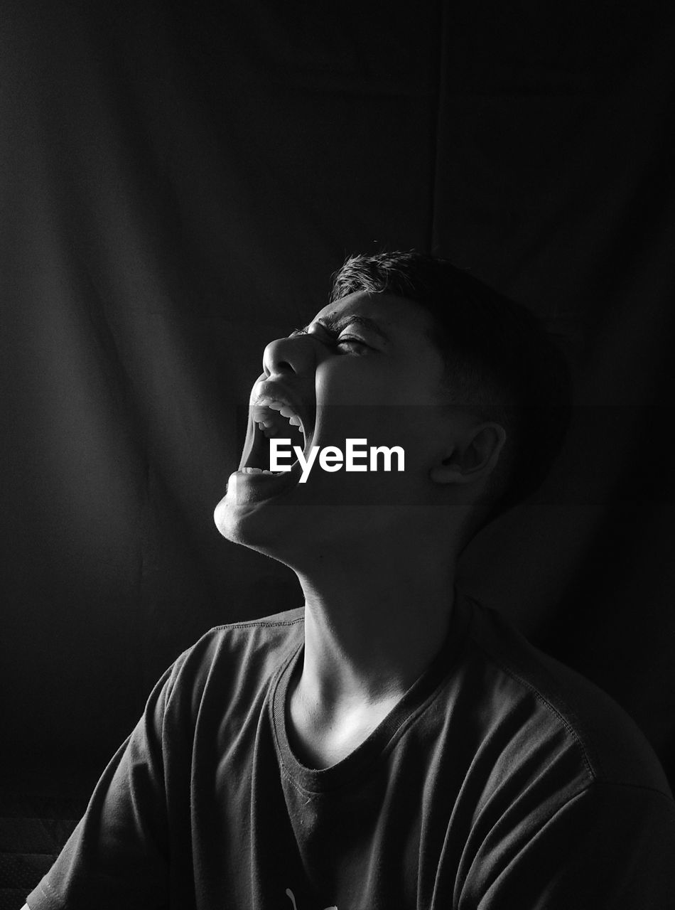 Young man looking away against black background