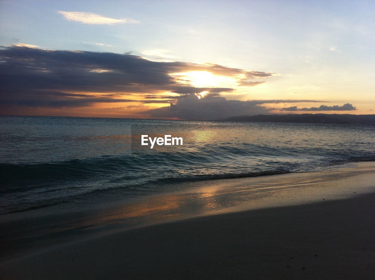 Scenic view of beach against sky at sunset