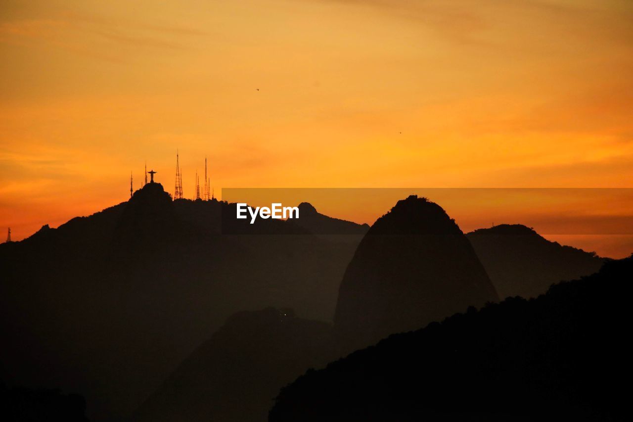 SILHOUETTE OF MOUNTAIN RANGE AGAINST ORANGE SKY