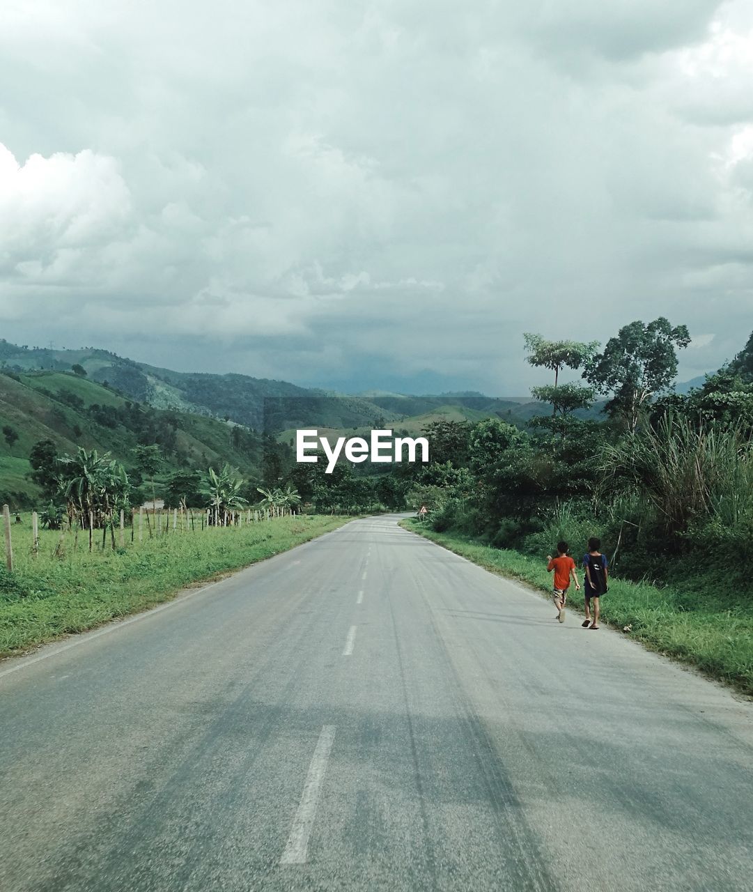 Two local boy walking talking on empty road near mount 