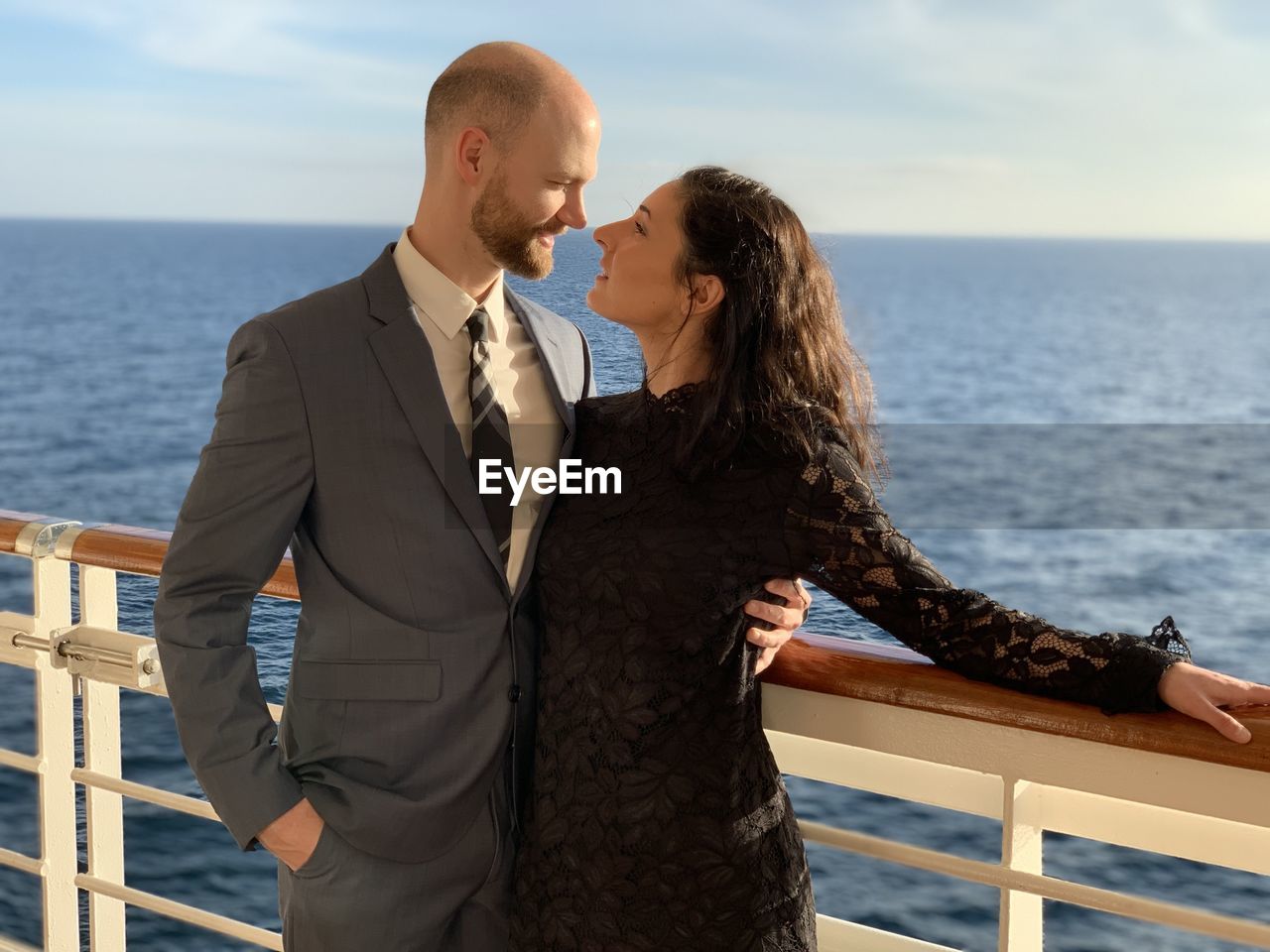 Couple standing by railing against sea