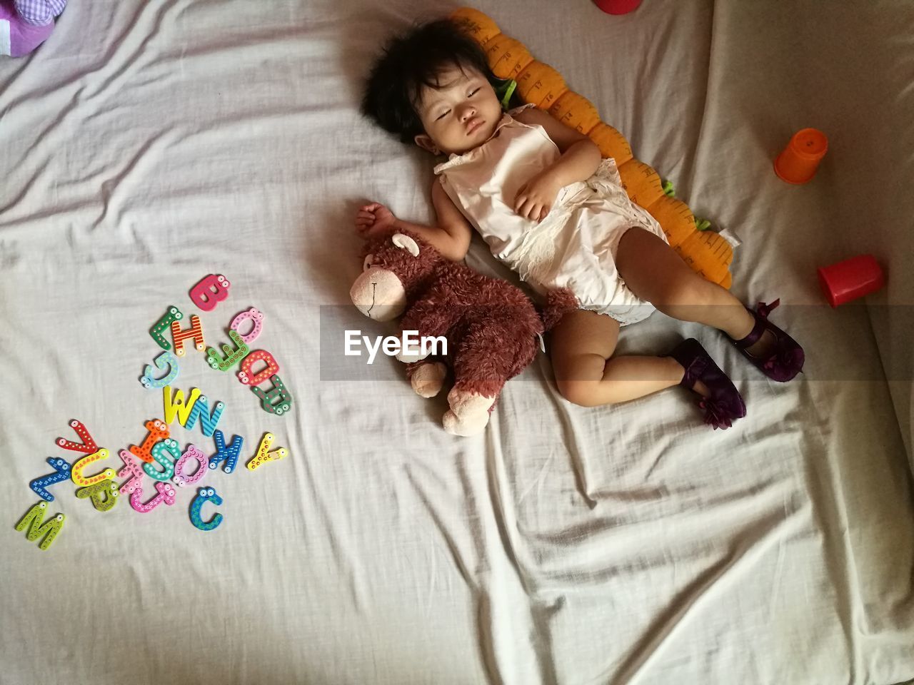 High angle view of baby sleeping by stuffed toy on bed at home