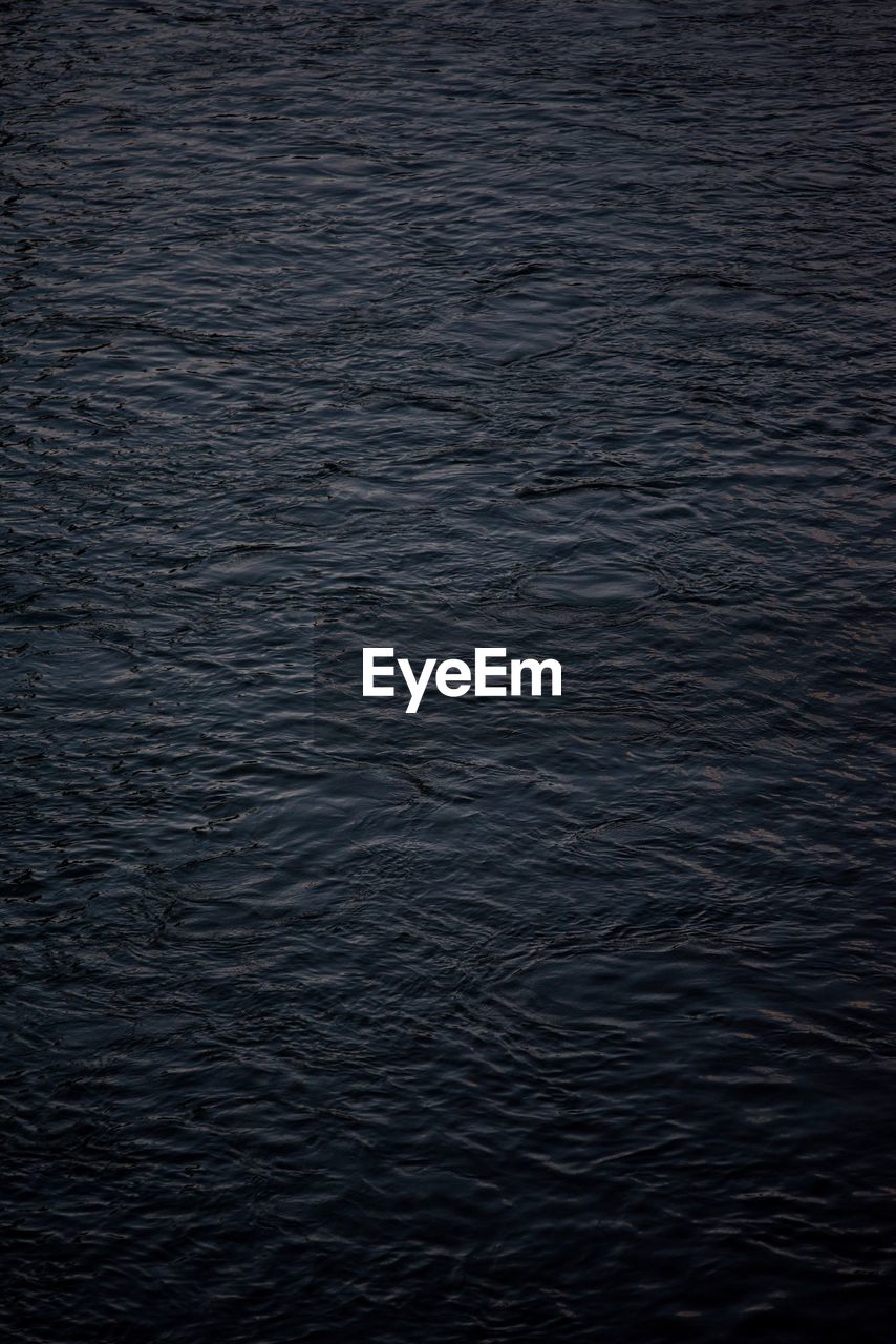 CLOSE-UP OF RIPPLED WATER IN THE DARK