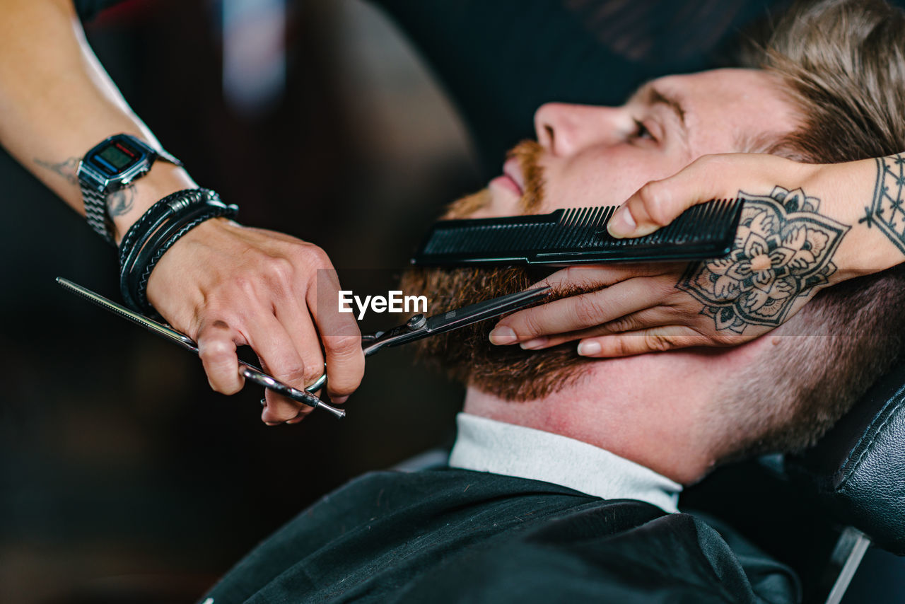 Close-up of woman shaving man beard