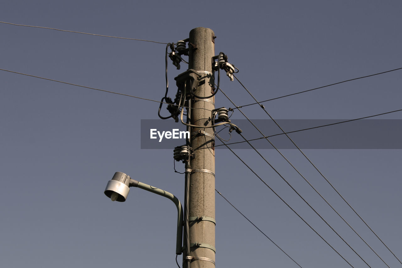 Low angle view of electricity pylon against blue sky