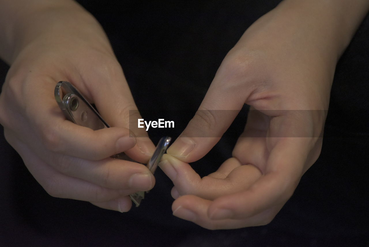 Close-up of woman filing nails over black background