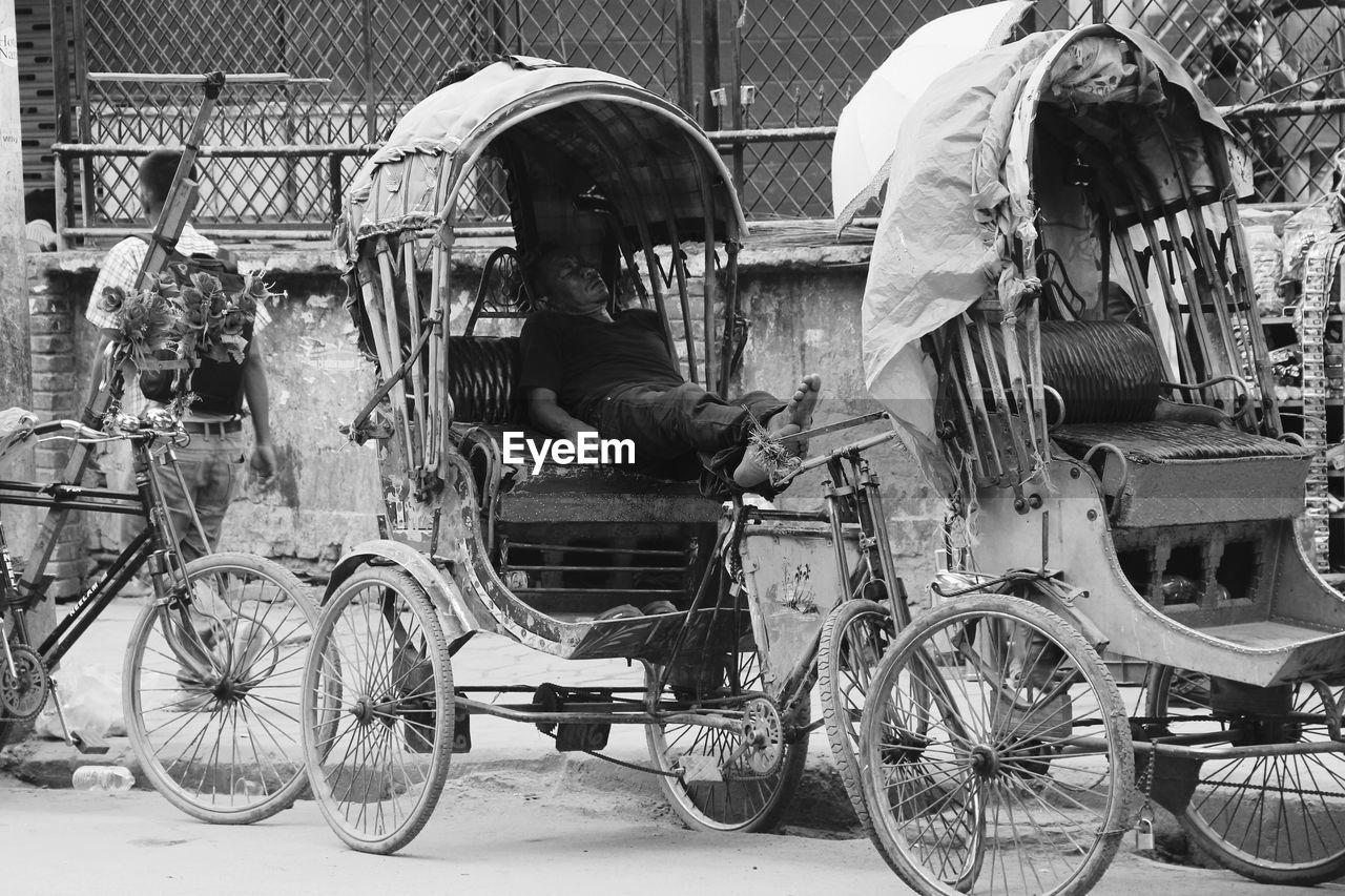 REAR VIEW OF A MAN CYCLING ON ROAD