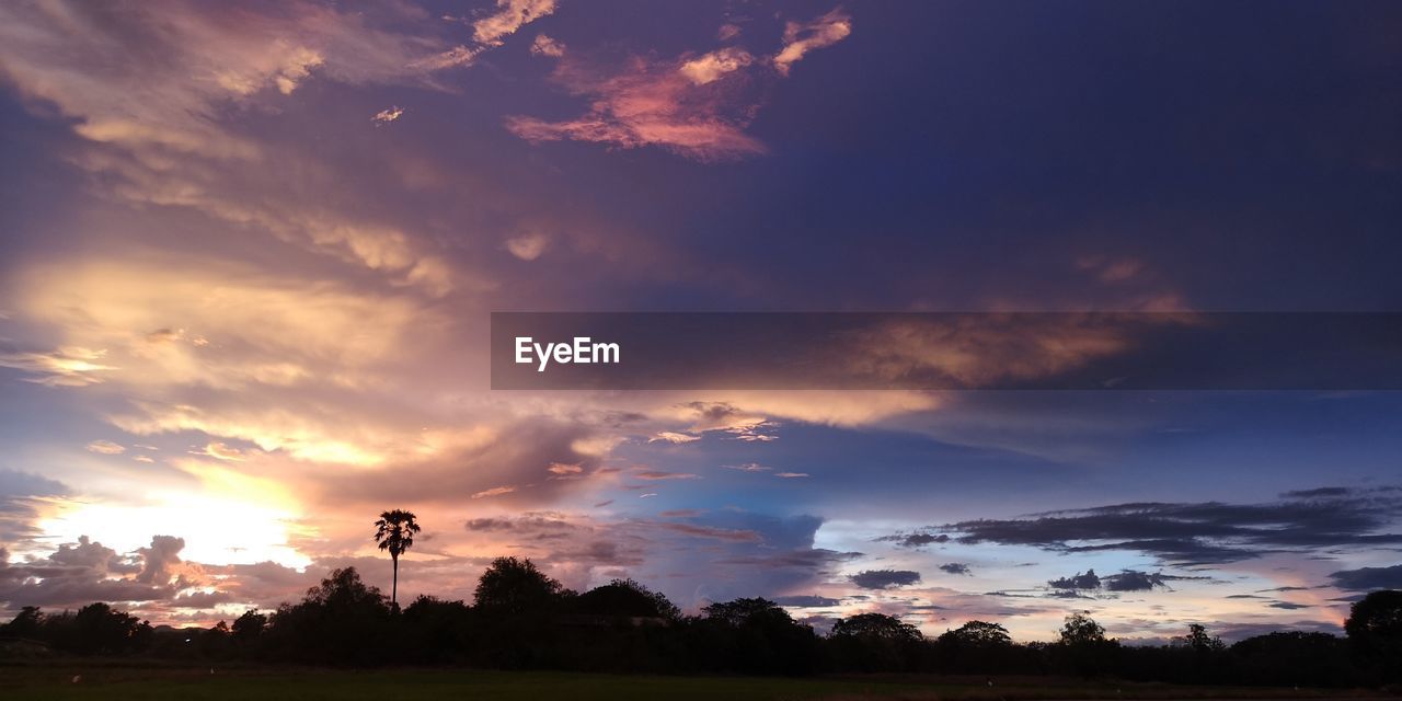 sky, cloud, sunset, environment, landscape, dawn, beauty in nature, nature, horizon, afterglow, scenics - nature, evening, dramatic sky, sunlight, tree, cloudscape, plant, land, no people, tranquility, sun, silhouette, outdoors, tranquil scene, field, orange color, rural scene, blue, red sky at morning, twilight, multi colored, grass, idyllic, architecture