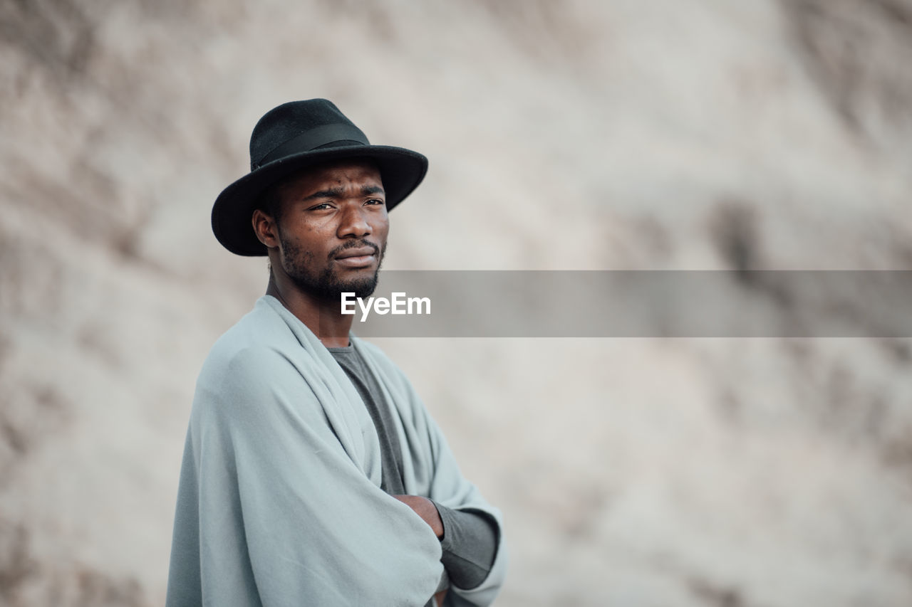 Portrait of man wearing hat standing against blurred background