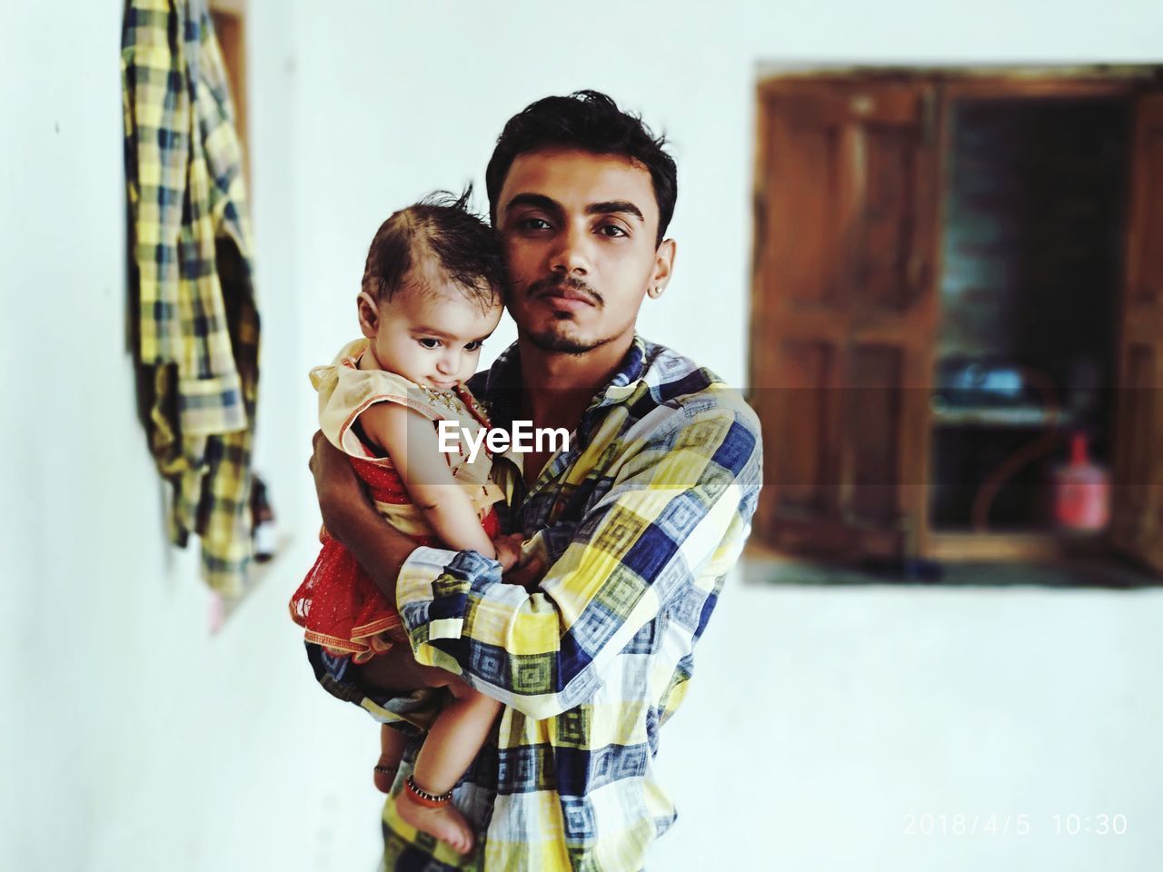 Father carrying daughter while standing at home