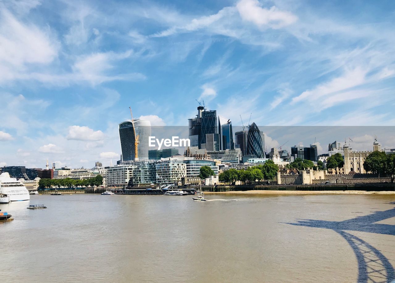 City at waterfront against cloudy sky