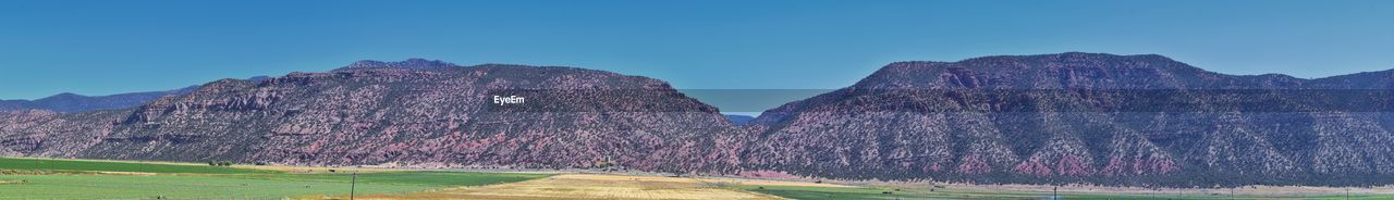 Panoramic view of rocky mountains against clear blue sky