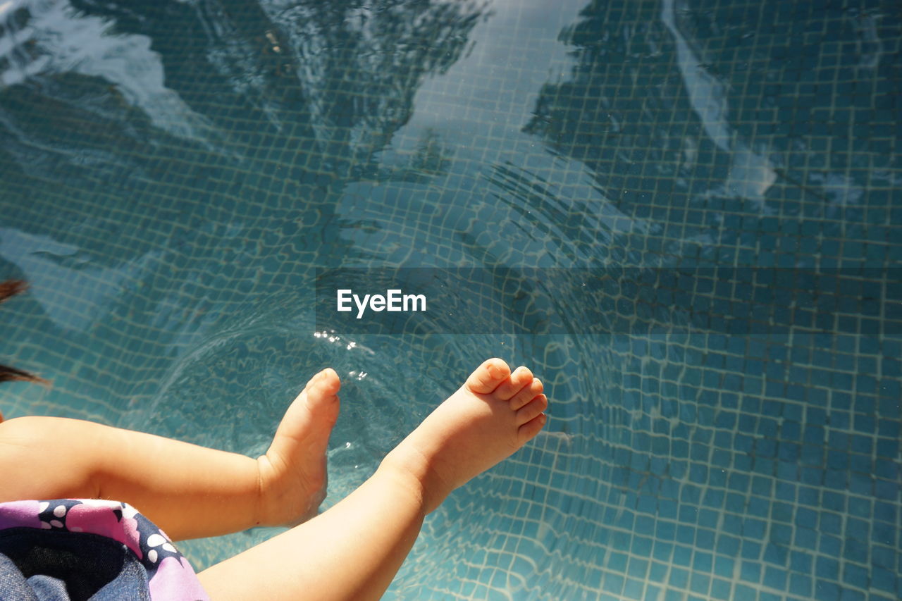 Low section of baby girl over swimming pool