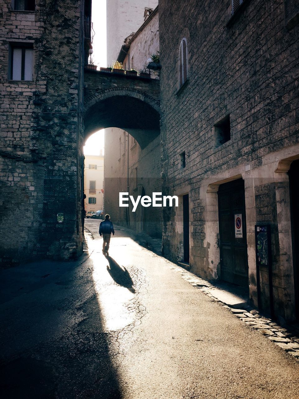 MAN WALKING AMIDST BUILDINGS IN CITY