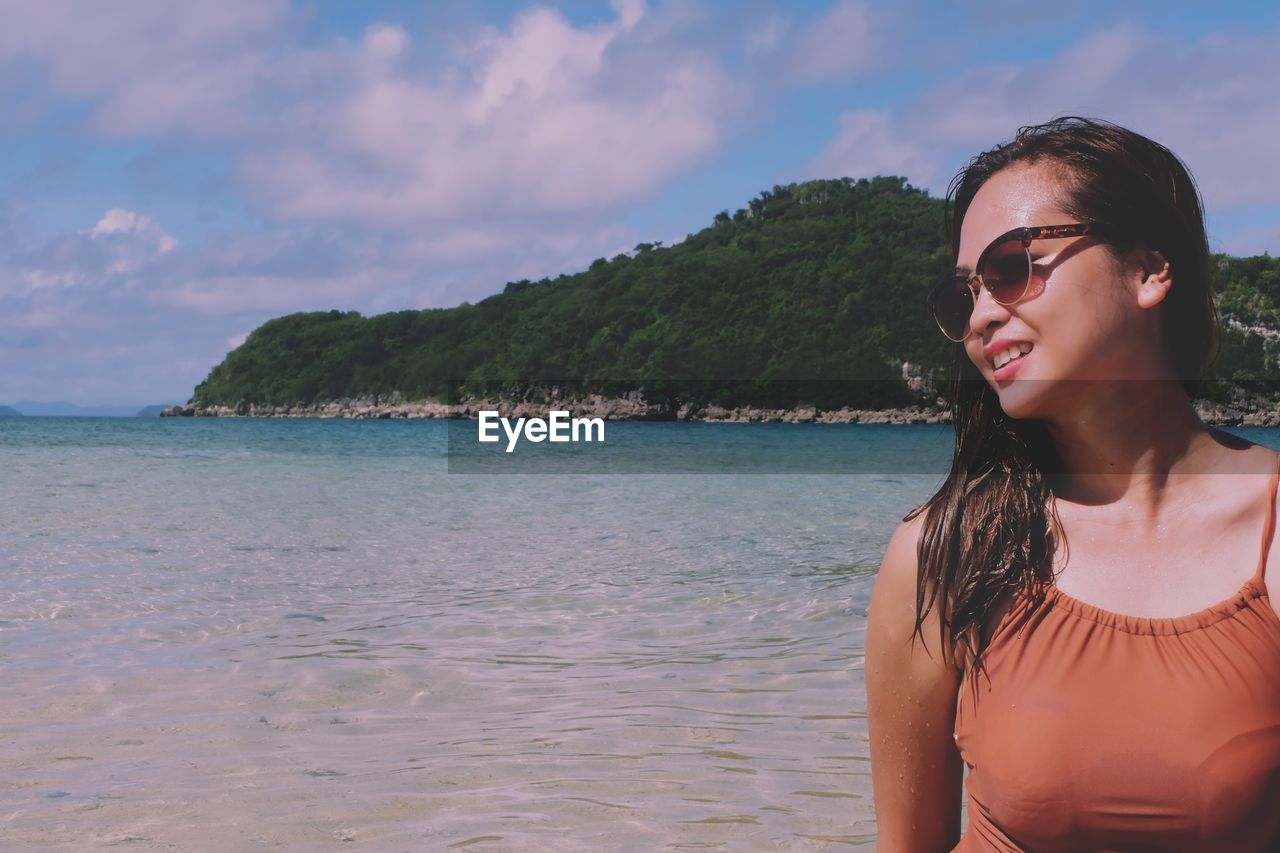 Woman in sunglasses at beach against sky