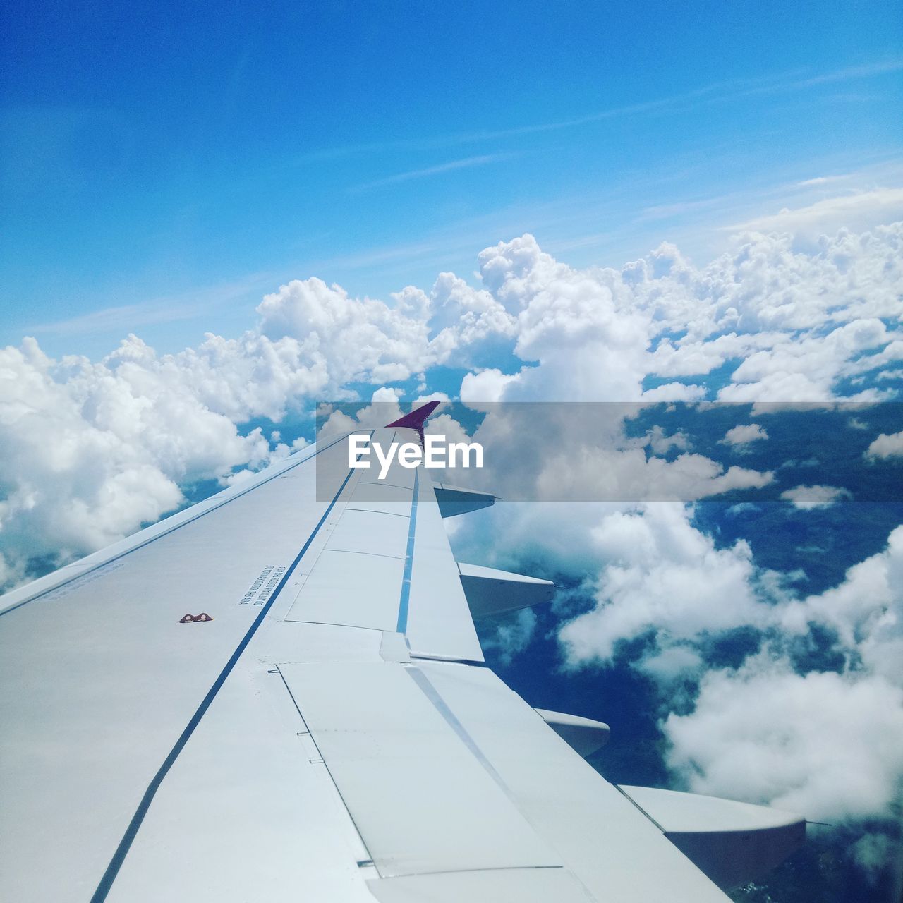 LOW ANGLE VIEW OF AIRPLANE FLYING OVER CLOUDS