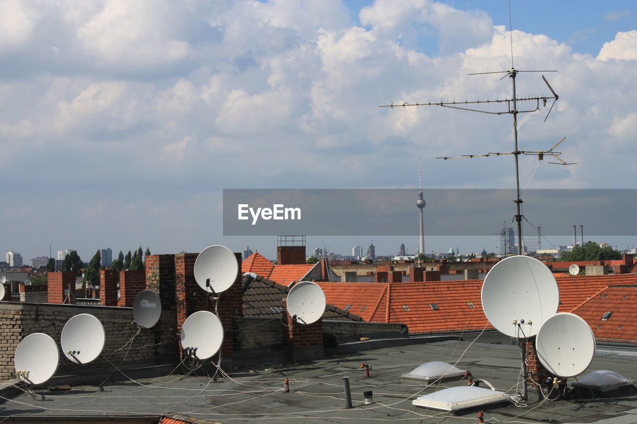 Aerial view of satellite receivers against sky and tv tower