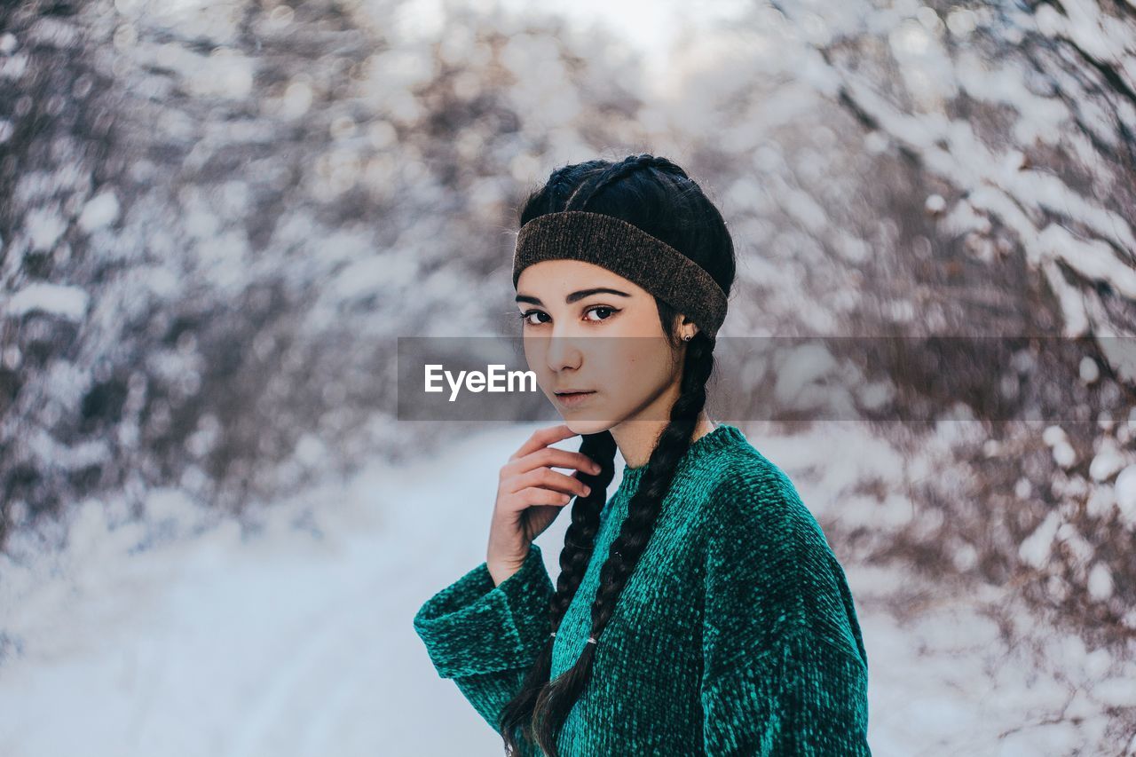 PORTRAIT OF YOUNG WOMAN STANDING BY SNOW