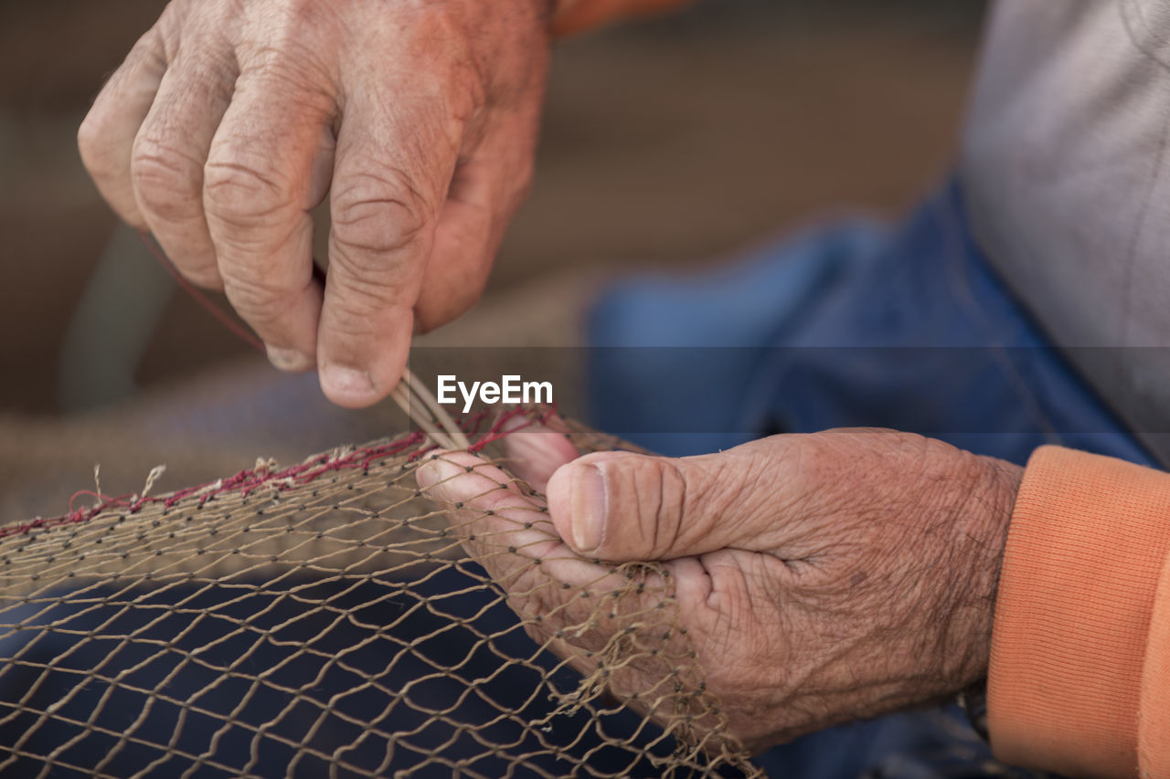 Midsection of man making net