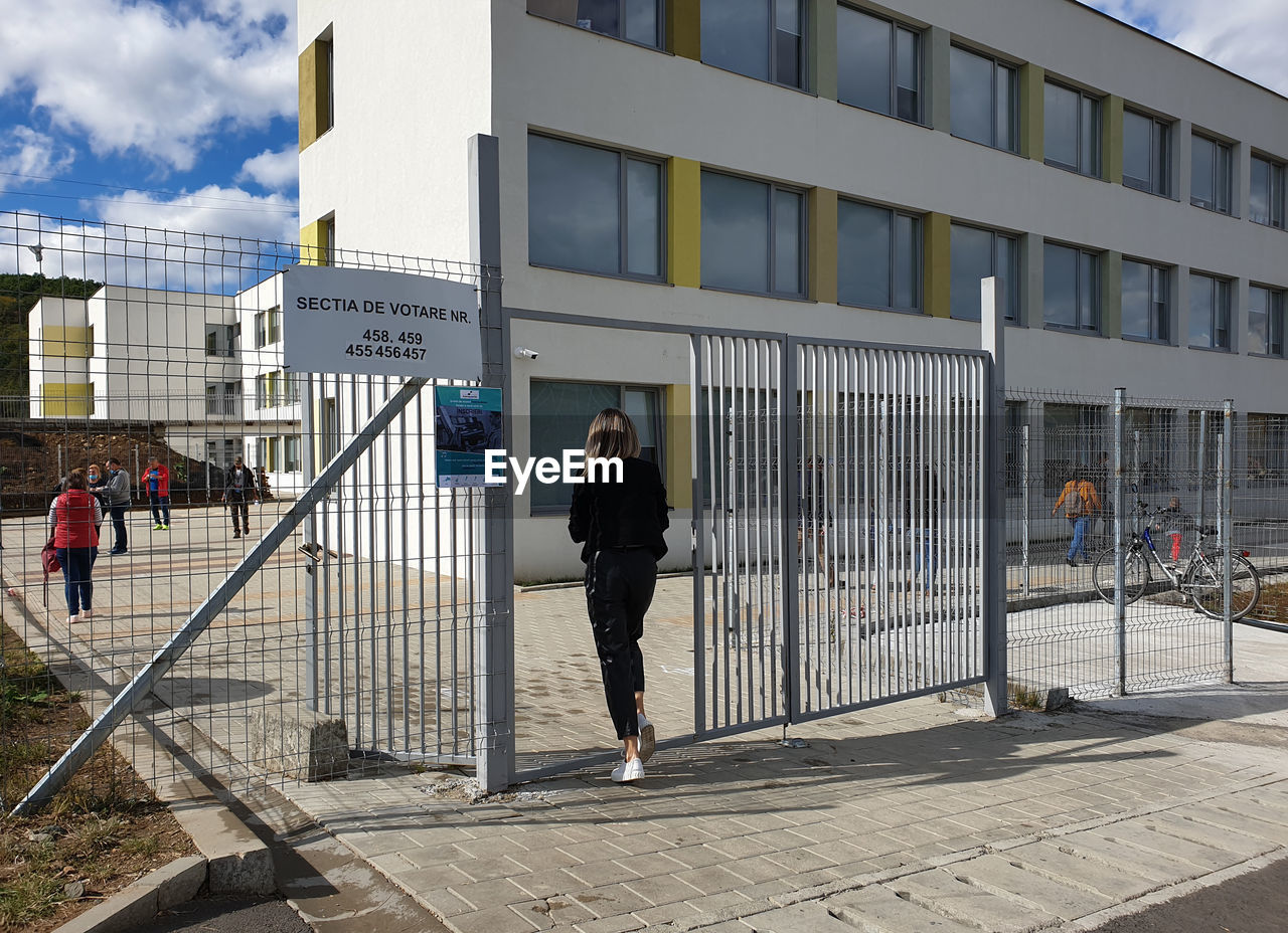 MAN WALKING ON FOOTPATH BY BUILDINGS IN CITY