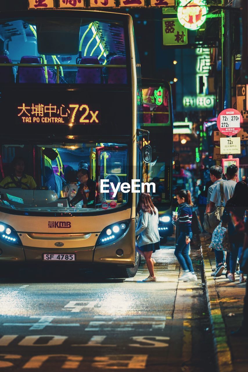 PEOPLE WALKING ON ILLUMINATED STREET