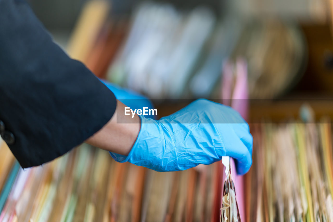 Midsection of woman wearing gloves analyzing files in drawer