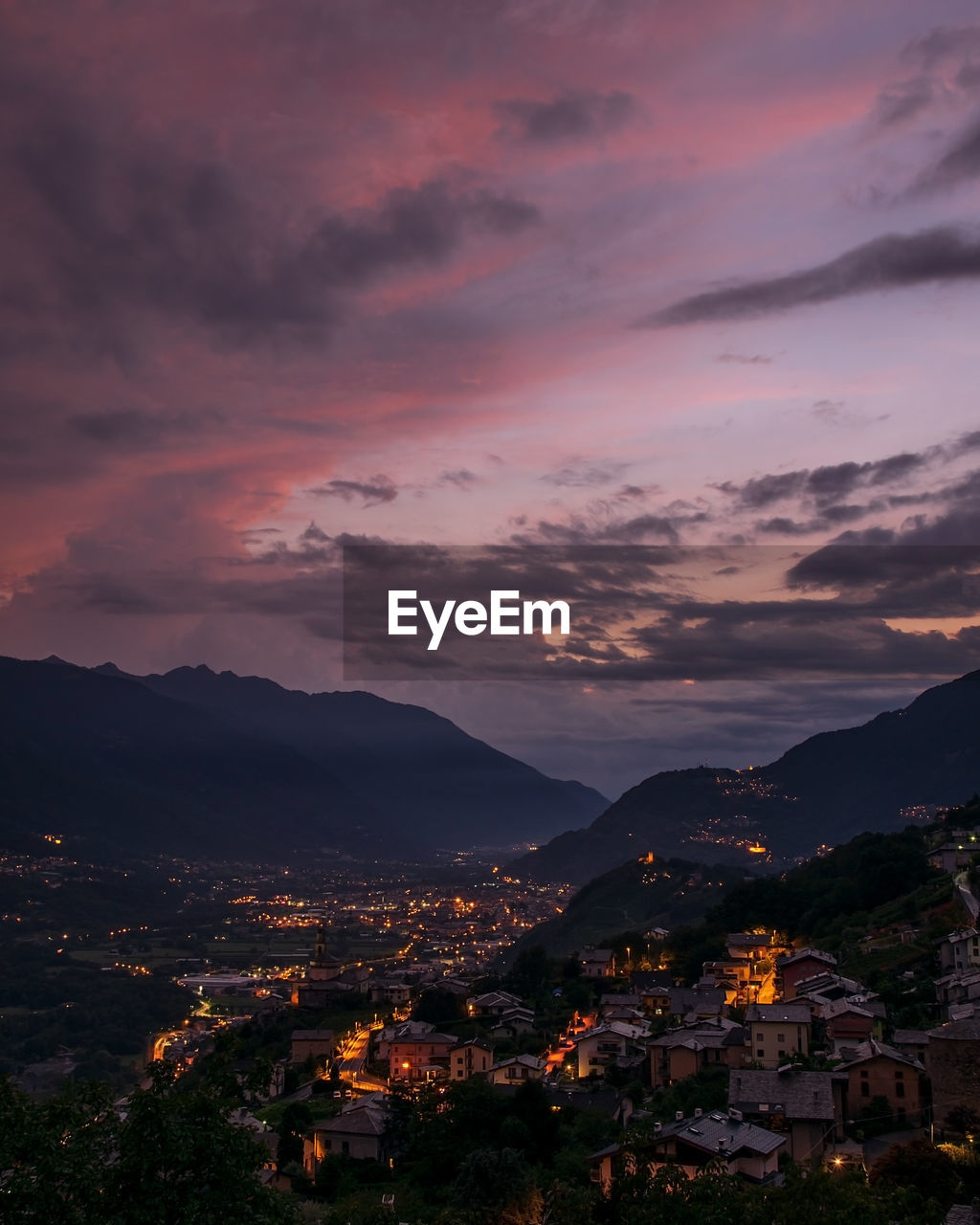 Illuminated cityscape against sky at sunset