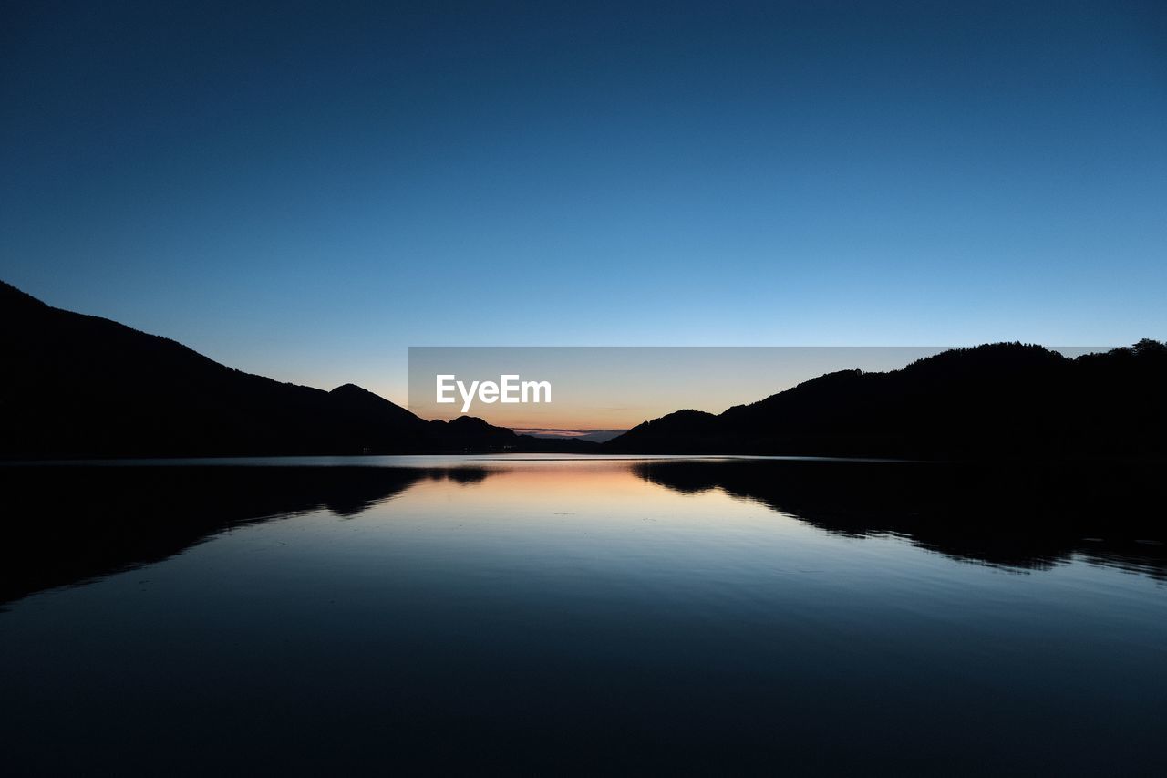 Scenic view of lake against clear sky during sunset
