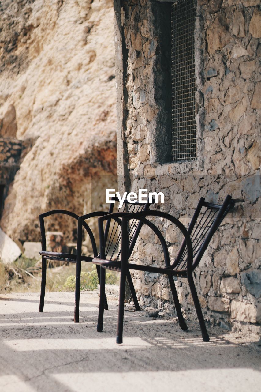 Empty chair against wall of old building