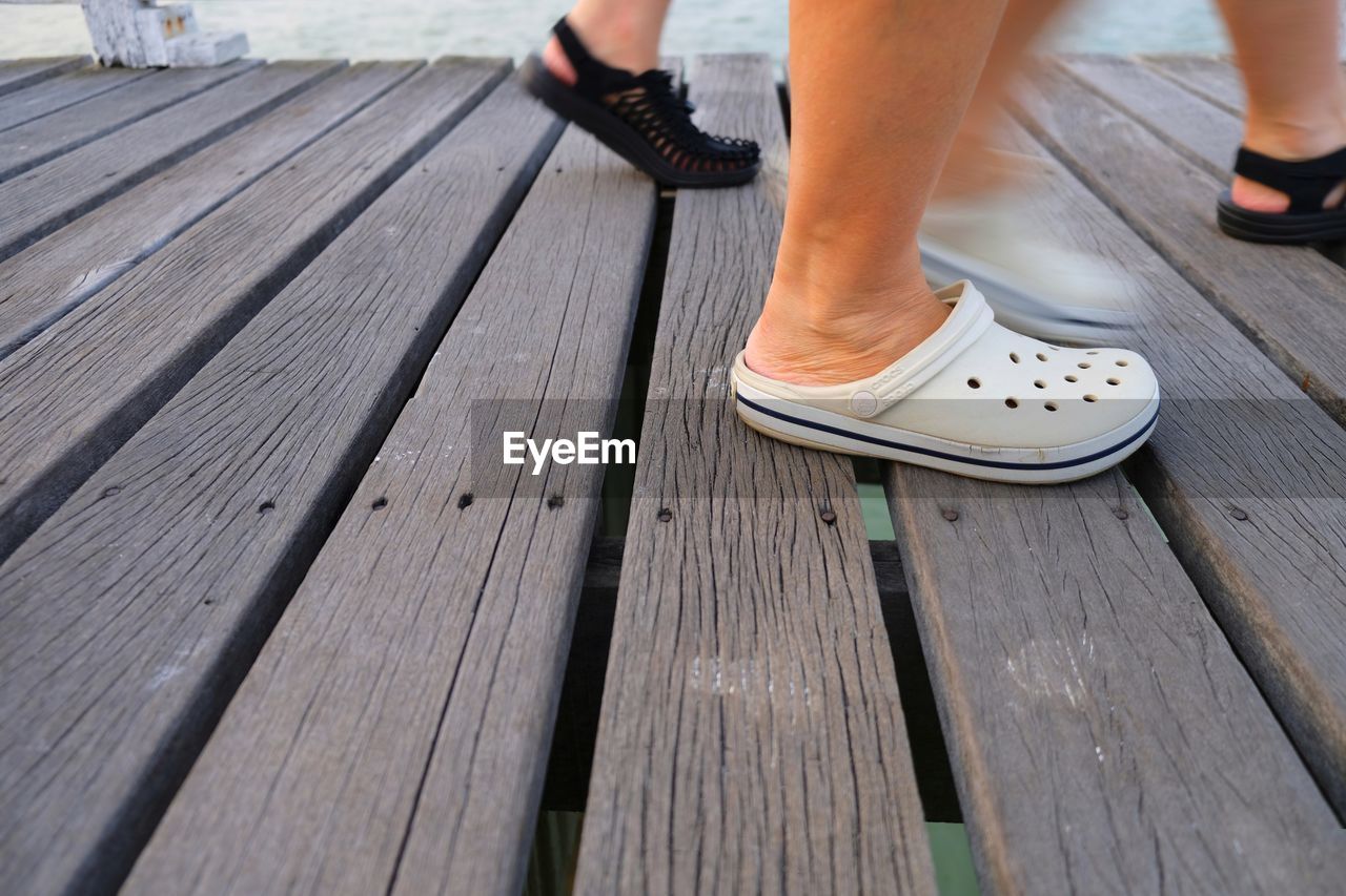 Low section of woman standing on wooden footpath