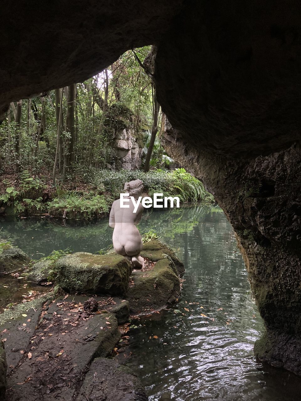 PERSON SITTING ON ROCK IN RIVER