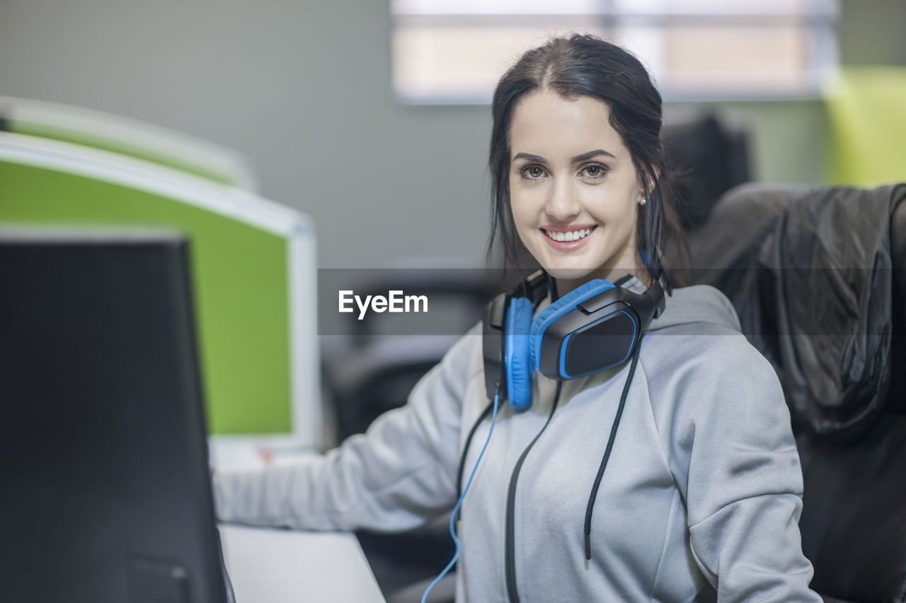 Portrait of smiling young wearing headphones in office
