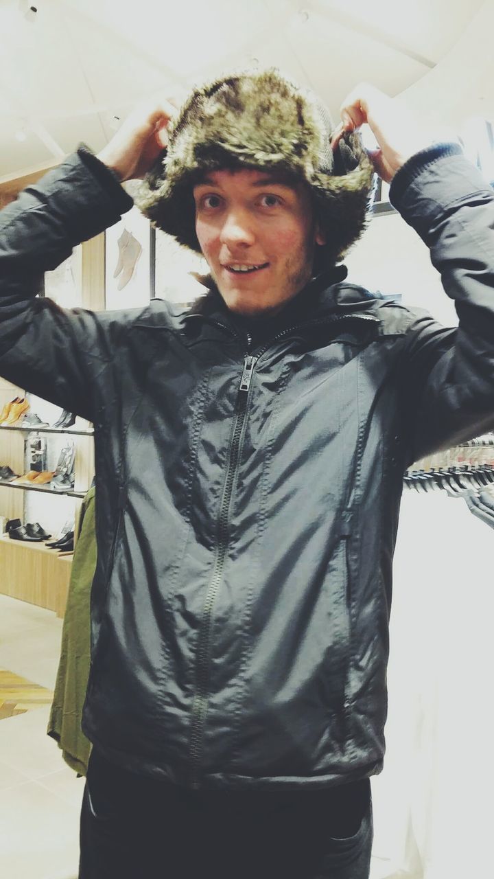 Portrait of young man wearing fur hat in store