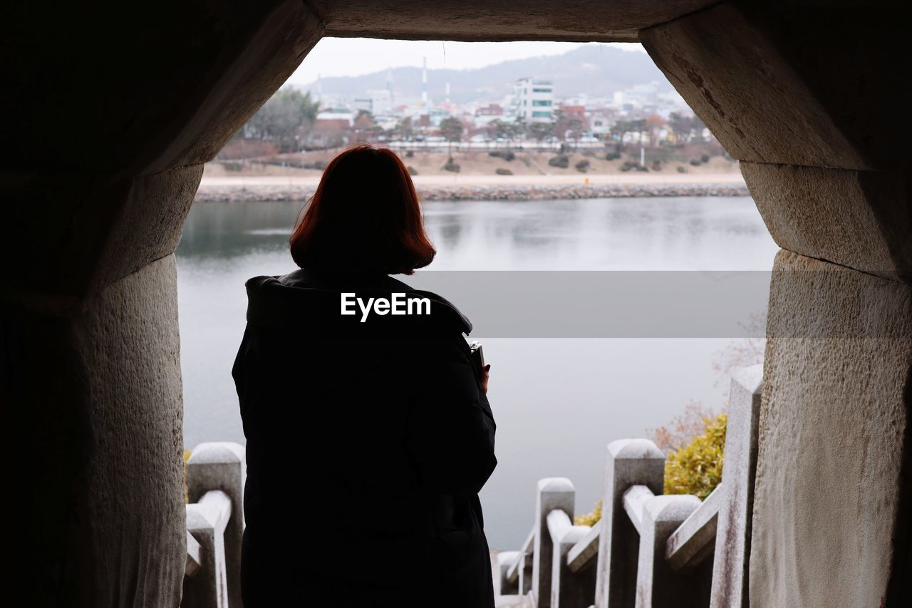 REAR VIEW OF WOMAN STANDING IN LAKE