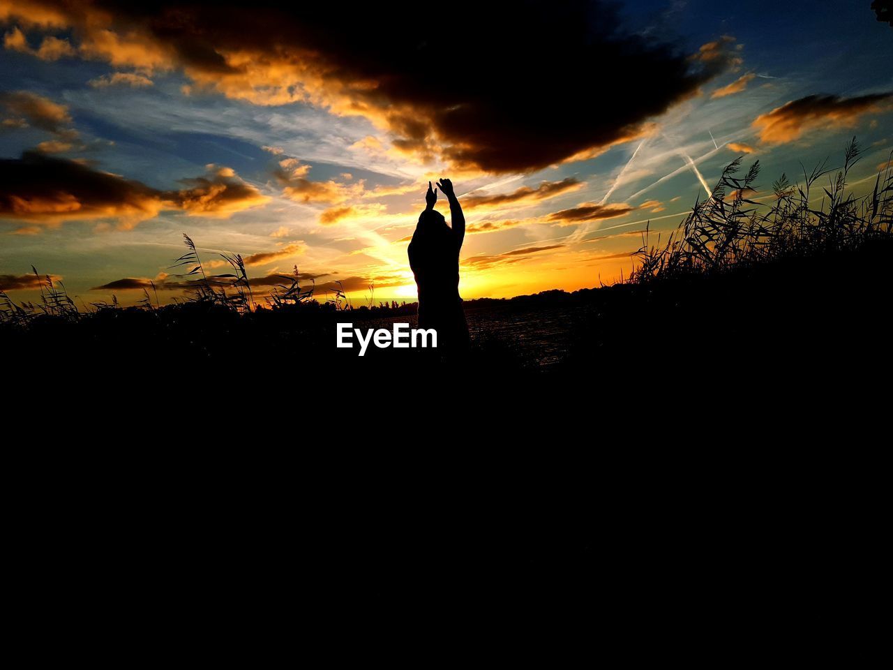 SILHOUETTE MAN STANDING ON FIELD DURING SUNSET