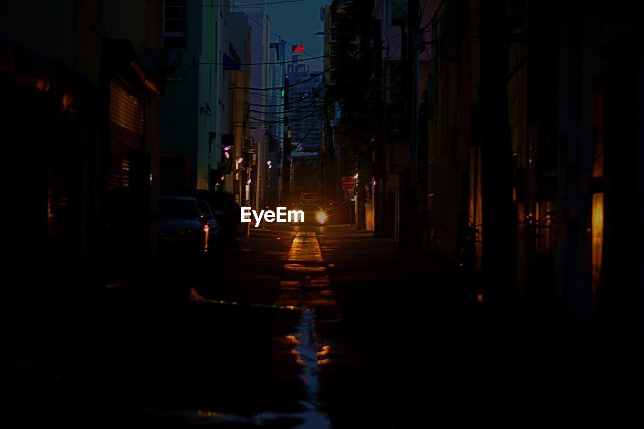 STREET AMIDST BUILDINGS IN CITY AT NIGHT