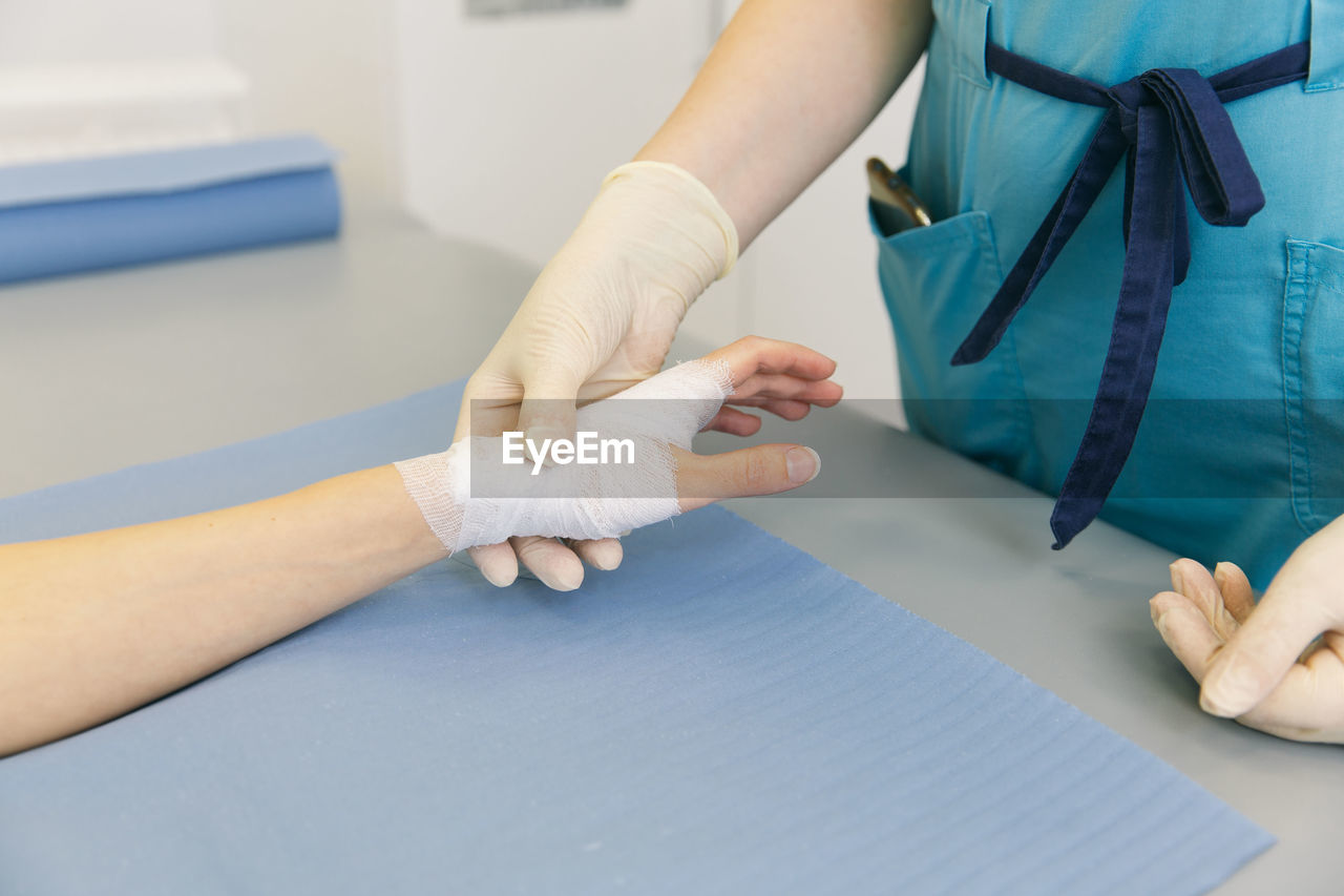 Midsection of doctor holding patient hand