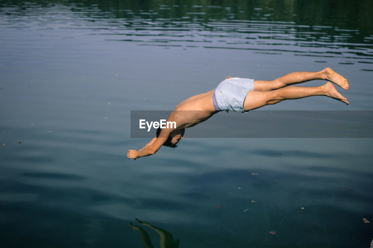 Shirtless man jumping in lake