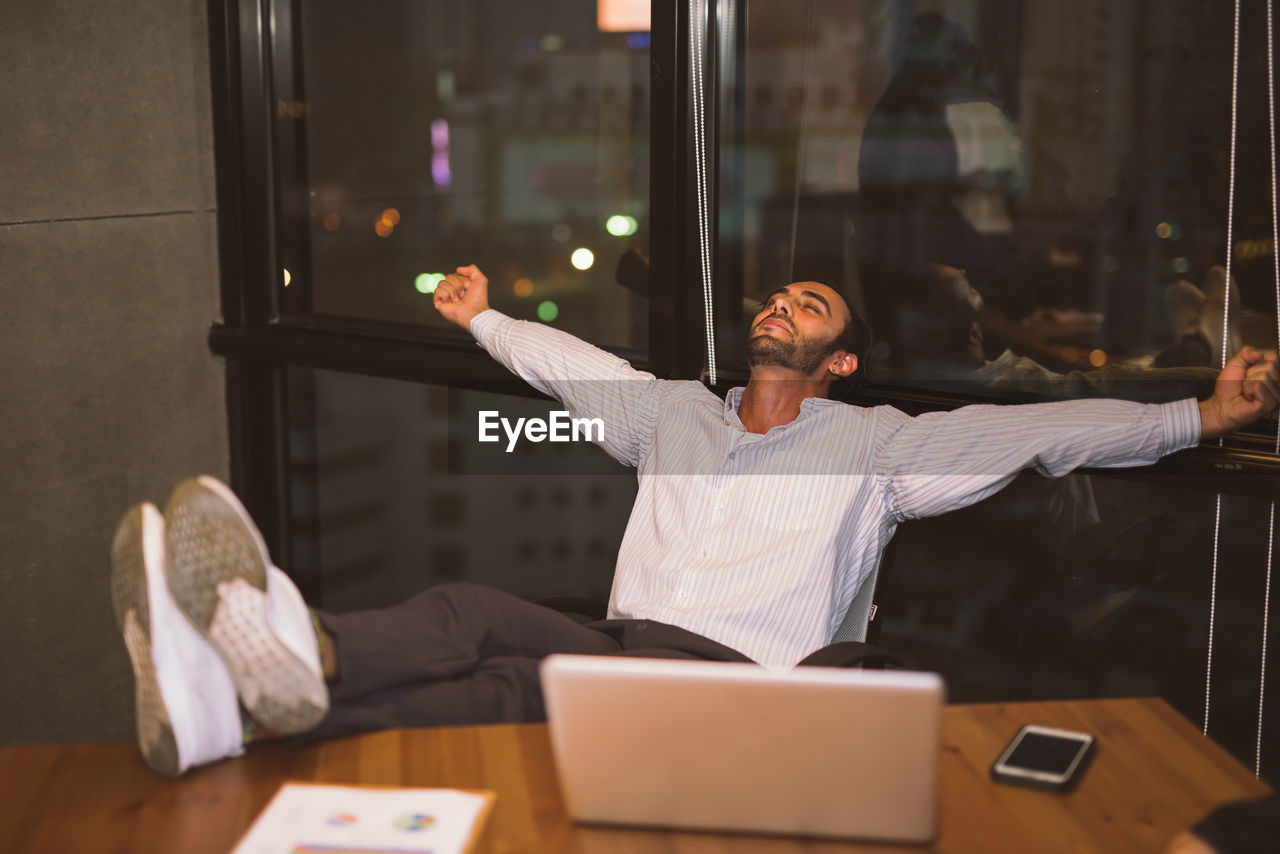 Businessman relaxing by laptop at office