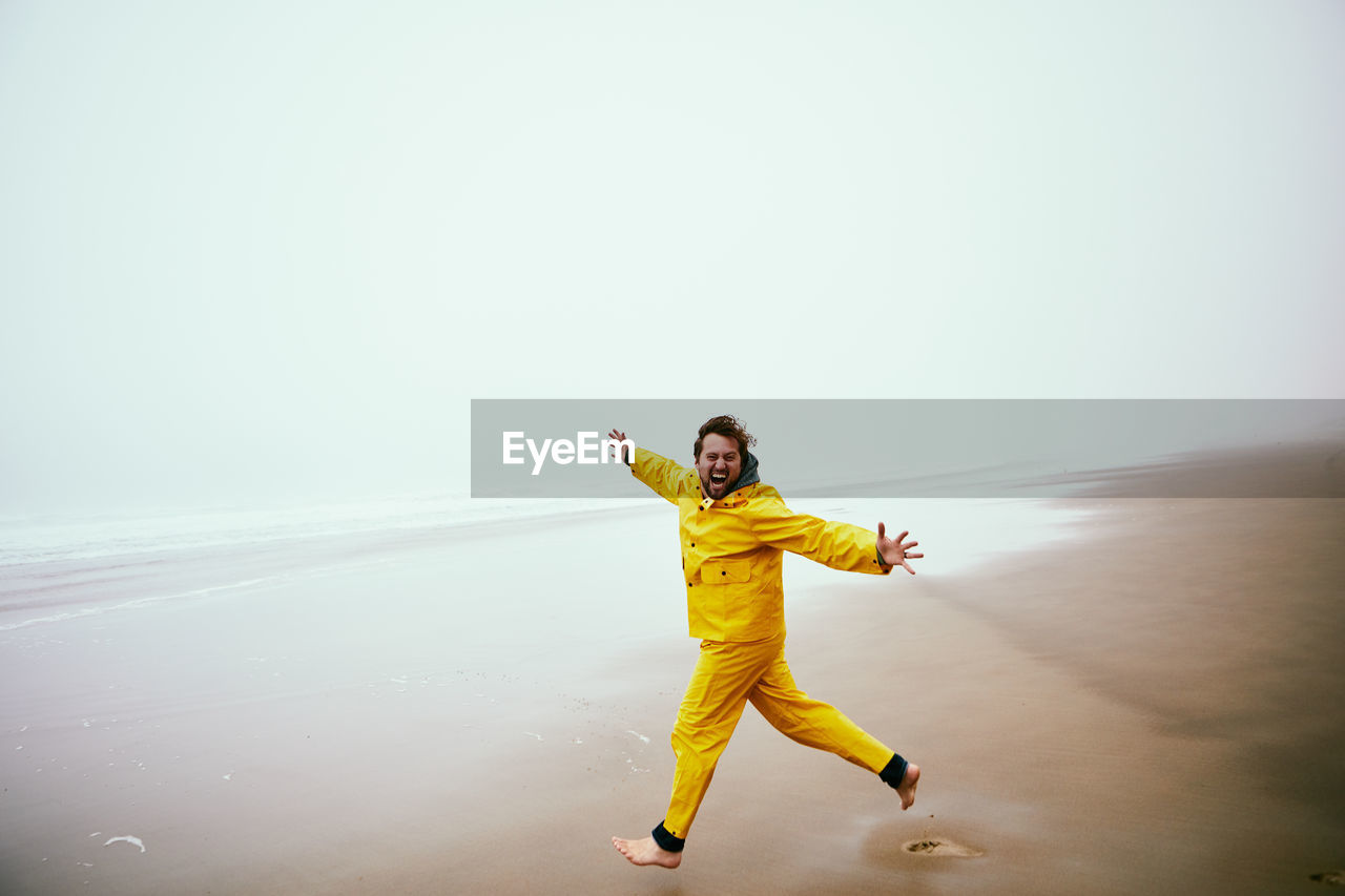 Man running at beach against sky