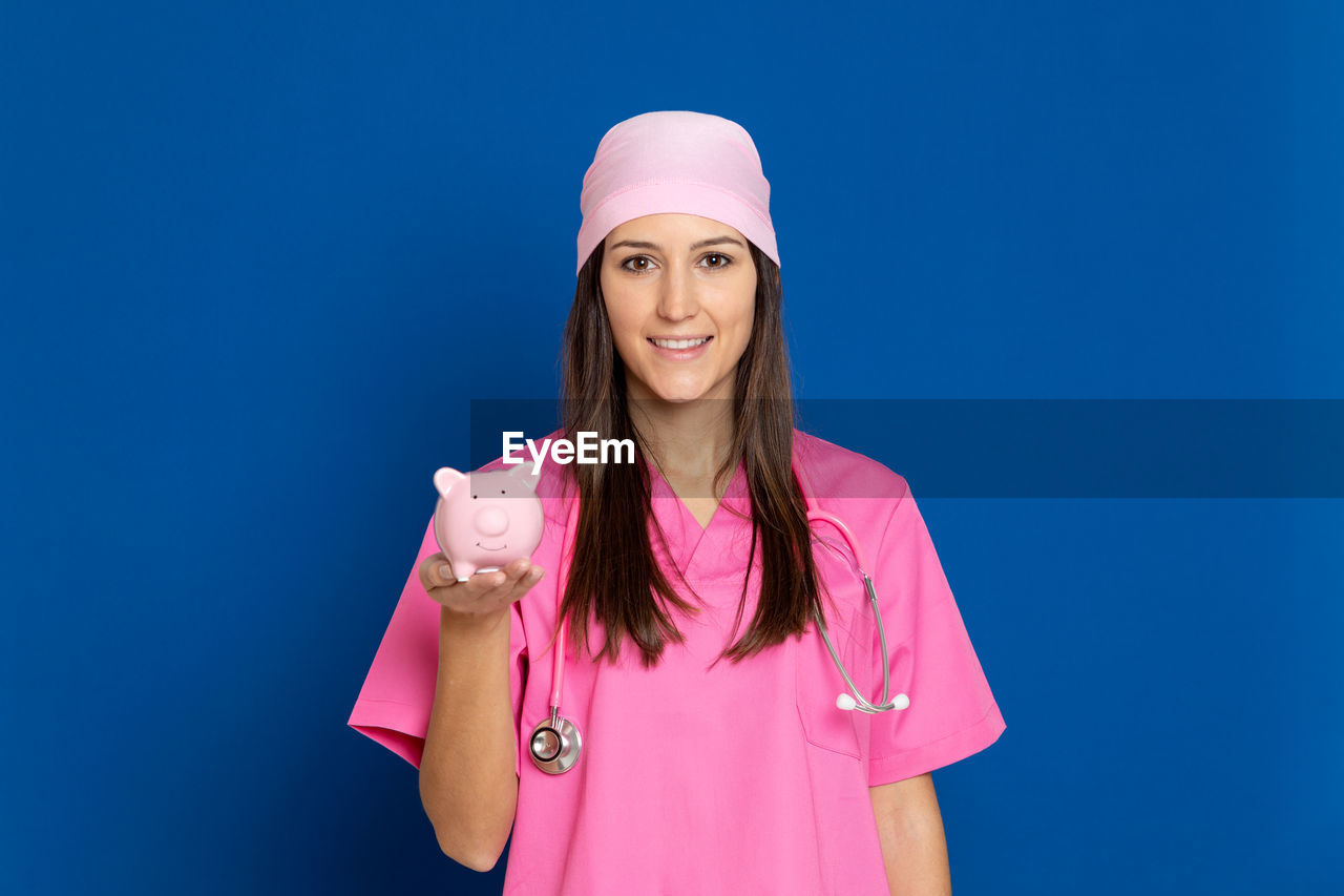 PORTRAIT OF BEAUTIFUL YOUNG WOMAN STANDING AGAINST PINK BLUE SKY