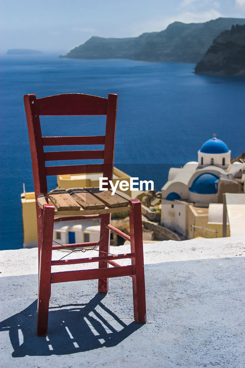 EMPTY CHAIRS AND TABLES AT BEACH AGAINST SKY